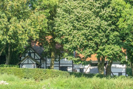 Het huis van de buren is ook van vakwerk en mooi verscholen onder de bomen