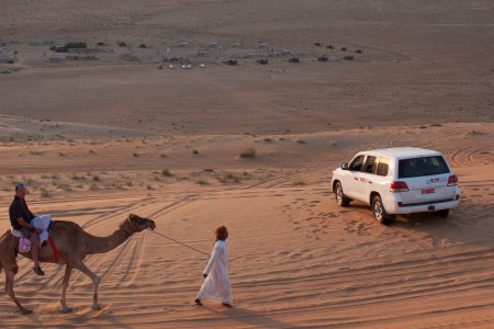 Op een zandduin, op de achtergrond het Safari Desert Camp