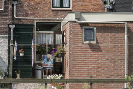 Aardige dame zit aan het water buiten te borduren